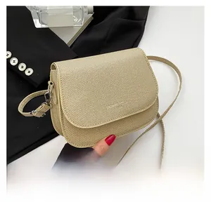 Gedetailleerde close-up van beige zadeltas met fijne textuur en metalen hardware