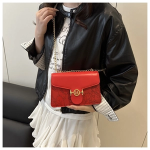 Detail of red embossed leather bag with golden M buckle and elegant chain strap