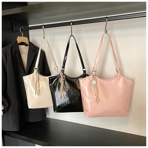 Detailed view of glossy patent leather tote bags in cream, black, and pink colors