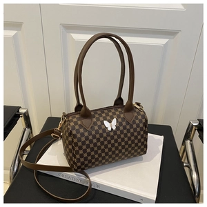 Detail of vintage barrel bag with monogram print and metallic butterfly decoration