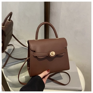 Detail shot of vintage brown leather handbag with gold circular twist lock and top handle