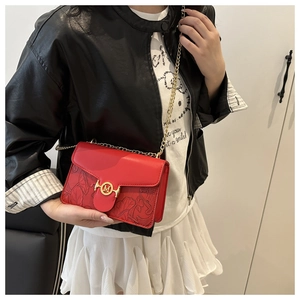 Detail of red crossbody bag featuring floral embossing and gold M-logo metal buckle