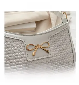 Détail de la texture croco blanc avec boucle nœud en métal doré sur un sac élégant chic