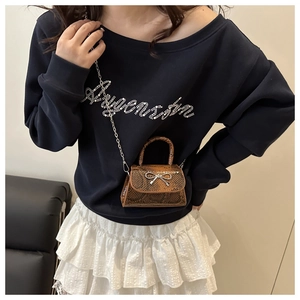 Detail der Mini-Tasche mit Schlangenmuster und Silberschleife an Model in Sweatshirt