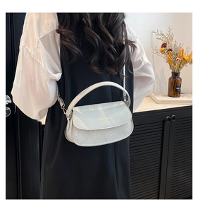 Detail der weißen Leder- und silbernen Glitzertasche mit goldenem Mode-Schriftzug