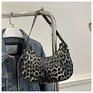 Détail du sac hobo à imprimé léopard avec ferrures dorées suspendu sur un cintre