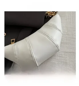 Close-up of segmented stitching and premium faux leather on white croissant bag