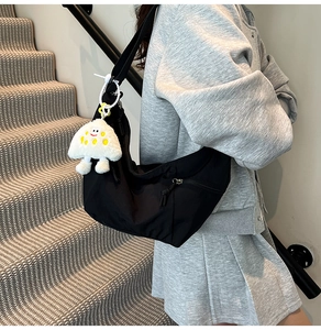 Detail of black crescent crossbody bag in nylon with a cute white plush cloud charm
