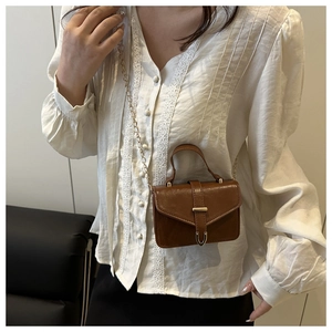 Detailed view of a brown vintage leather mini square bag with golden chain and metal buckle