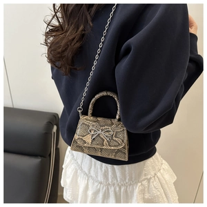 Detail of snake skin texture mini square bag with silver metal bow and chain strap