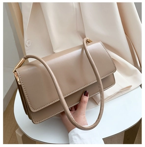Detail of minimalist apricot leather shoulder bag with elegant gold metal hardware accents