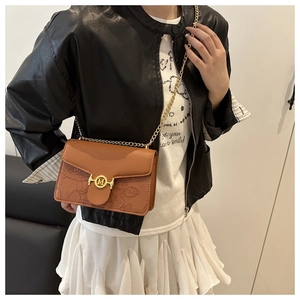 Detail of caramel leather bag with embossed rose pattern and golden M-logo chain strap