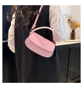 Detailed view of a pink minimalist crossbody bag with gold lettering and smooth leather finish