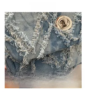 Gros plan sur la texture denim matelassée avec bords effilochés et fermoir en métal argent