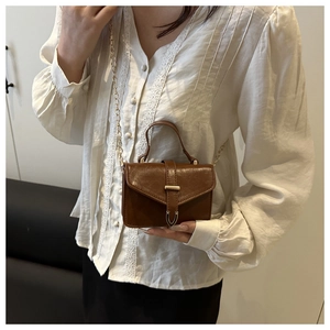 Detail of dark brown leather mini crossbody bag with golden chain and U-shaped clasp
