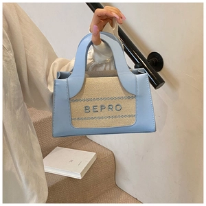Close-up of light blue leather and straw handbag with BEPRO embroidered logo detail