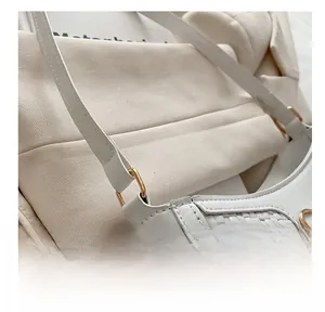 Gros plan d'un sac blanc avec détails en cuir tressé et anneau en métal doré