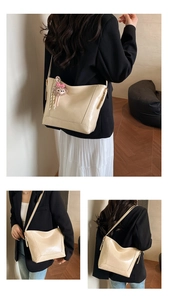Detail view of light beige PU leather tote bag with cute plush pendant and long shoulder strap
