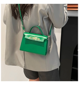 Détail d'un petit sac carré vert vif avec fermoir doré et poignée supérieure