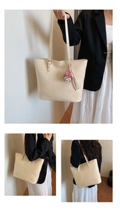 Macro detail of creamy faux leather tote bag with metallic buckle and slim shoulder strap
