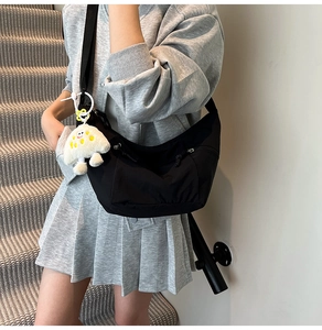 Close-up of black crescent nylon crossbody bag featuring a cute white mushroom plush charm