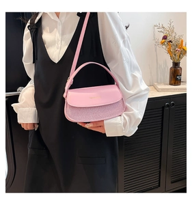 Detail of pink leather handbag with glitter fabric panel and gold lettering