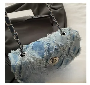 Détail du sac bandoulière en denim matelassé bleu clair avec bords effilochés