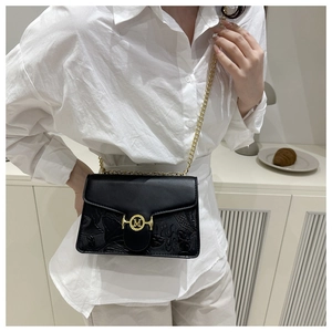 Detail of black leather bag featuring floral embossing and gold M-letter logo buckle