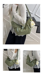 Detailed view of a green crescent crossbody bag with nylon fabric and plush pendant