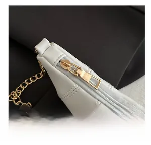 Detailed close-up of smooth gold zipper and fine stitching on white leather crescent bag