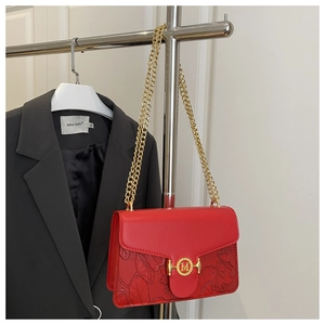 Close-up of red leather baguette bag featuring floral embossing and gold M buckle