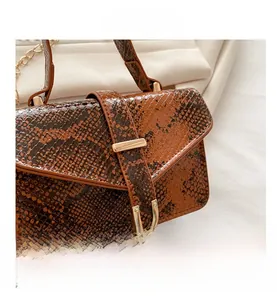 Detailed view of the gradient brown snake pattern leather and metal chain on a handbag