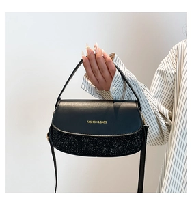 Detail of black crossbody bag featuring matte leather and glitter texture patchwork