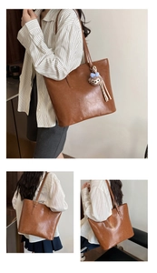 Detail of a brown leather tote bag with a cute teddy bear charm in a lifestyle setting