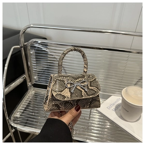 Detail of snake print mini handbag with silver bow accent and metal chain strap