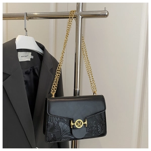 Macro shot of black leather baguette bag with relief texture and golden M buckle