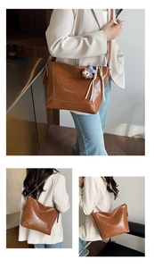 Detail view of large dark brown leather tote bag worn as a shoulder and crossbody bag