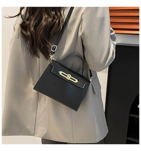 Vue latérale d'un sac à main minimaliste en cuir noir avec fermoir doré sur un mannequin