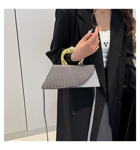 Detail of grey crocodile texture bag with unique gold metallic flowing handle design