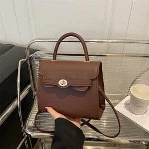 Deep brown faux leather crossbody bag with top handle and gold oval twist lock closure