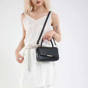 Bolso de mano minimalista en cuero PU negro con hebilla metálica dorada sobre fondo blanco