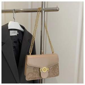 Close-up of beige leather crossbody bag with floral embossing and gold M-logo buckle