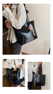Detail of glossy black tote bag featuring a cute plush bear charm and long shoulder straps