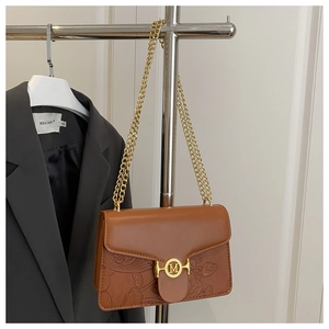 Detailed close-up of brown leather bag with embossed lotus and fish patterns and gold buckle