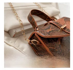 Detail of the golden metal hook and brown snakeskin texture on a luxury handbag