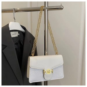 Detailed view of floral embossing and golden M-letter buckle on white baguette bag