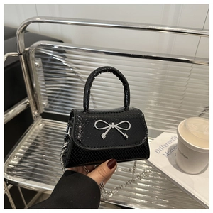 Detail of snake pattern texture on black mini bag with silver bow and chain strap
