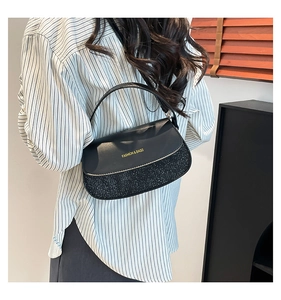 Close-up of black underarm bag featuring textured contrast panels and gold FASHION & BAGS logo