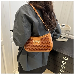 Gros plan d'un sac porté épaule en cuir marron avec boucle nœud doré sur un modèle