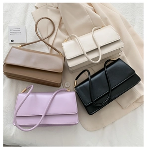 Detail showing various colors of stylish rectangular shoulder bags on a fabric background